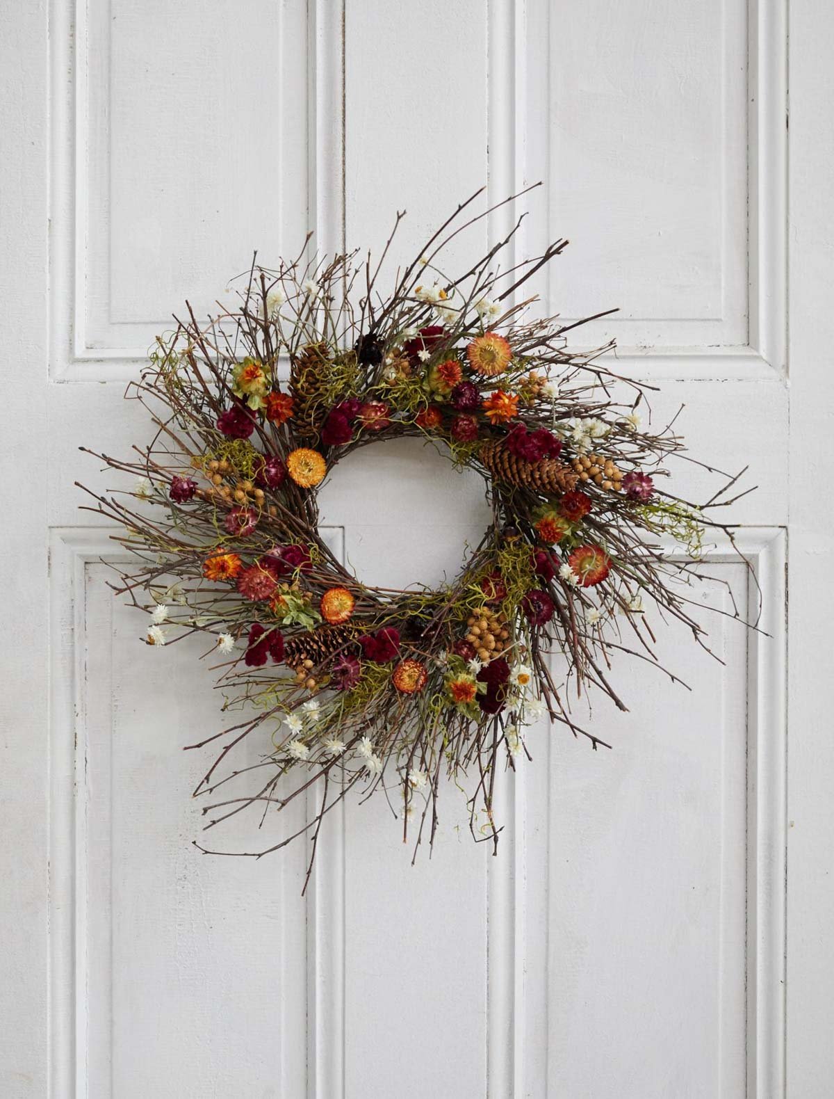 dried flower wreath for fall, hanging on white door