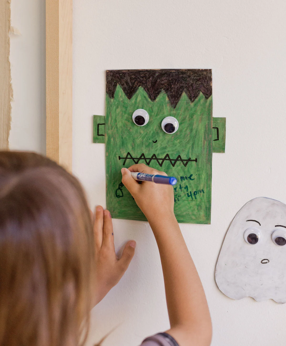 child writing on a small halloween dry erase board made from a child's drawing