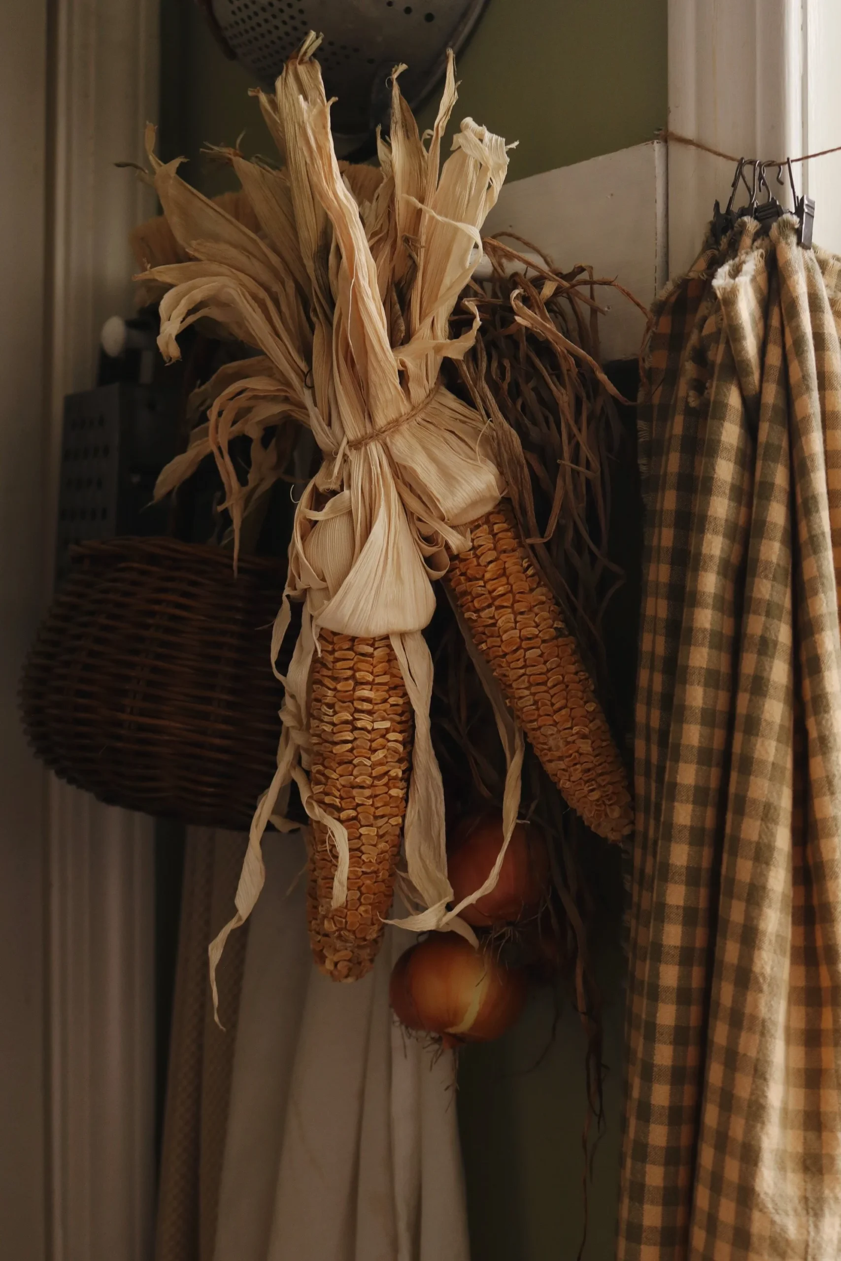 dried corn hanging from a shelf, with other fall decor