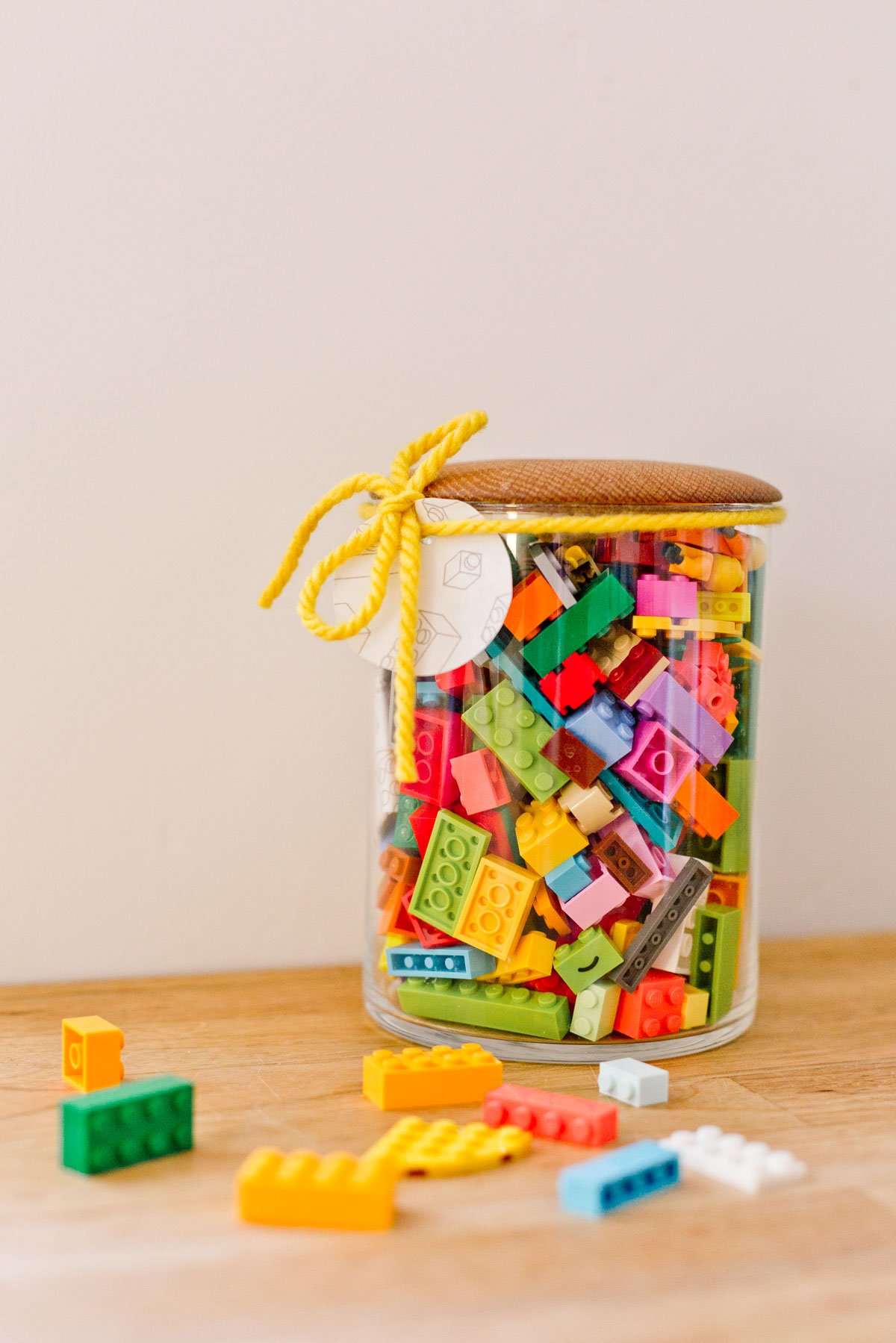 glass jar with wood lid, filled with colorful legos for kids
