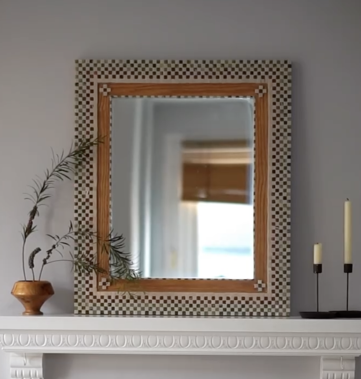 diy tile mirror on a white fireplace with candles and a vase