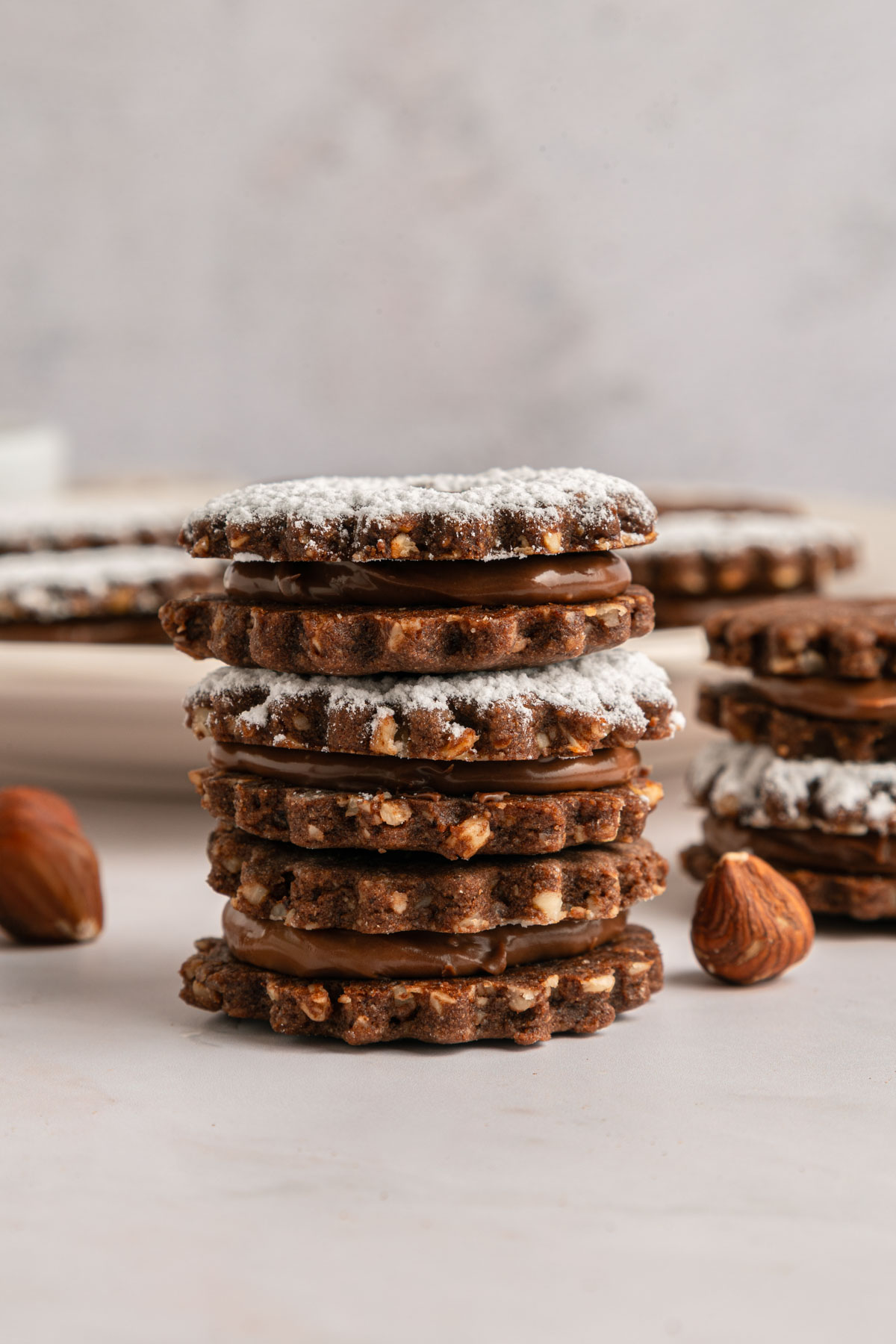 stacked hazelnut chocolate linzer cookies with powdered sugar on top