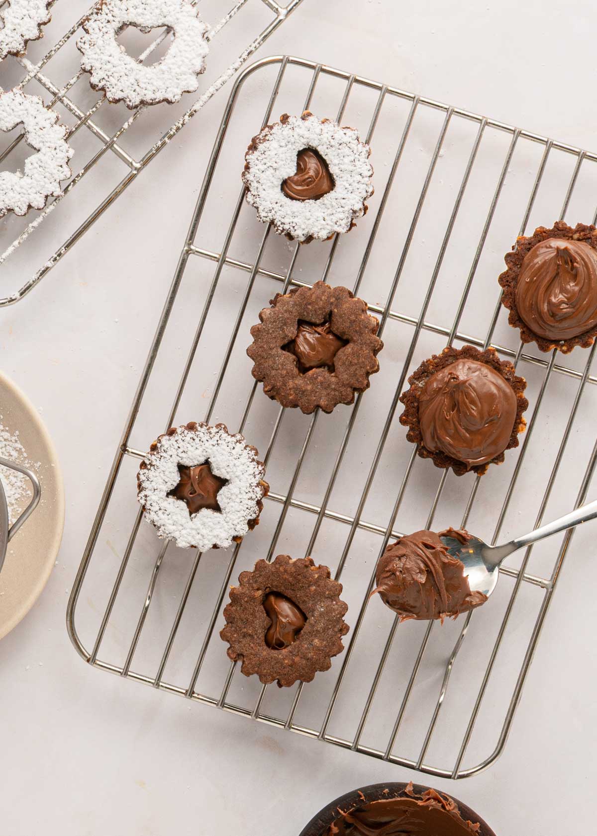 putting nutella on linzer cookie sandwiches on a countertop