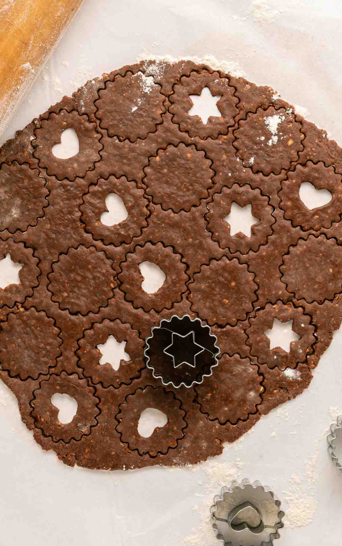 rolled out chocolate hazelnut dough being cut with shaped cookie cutters