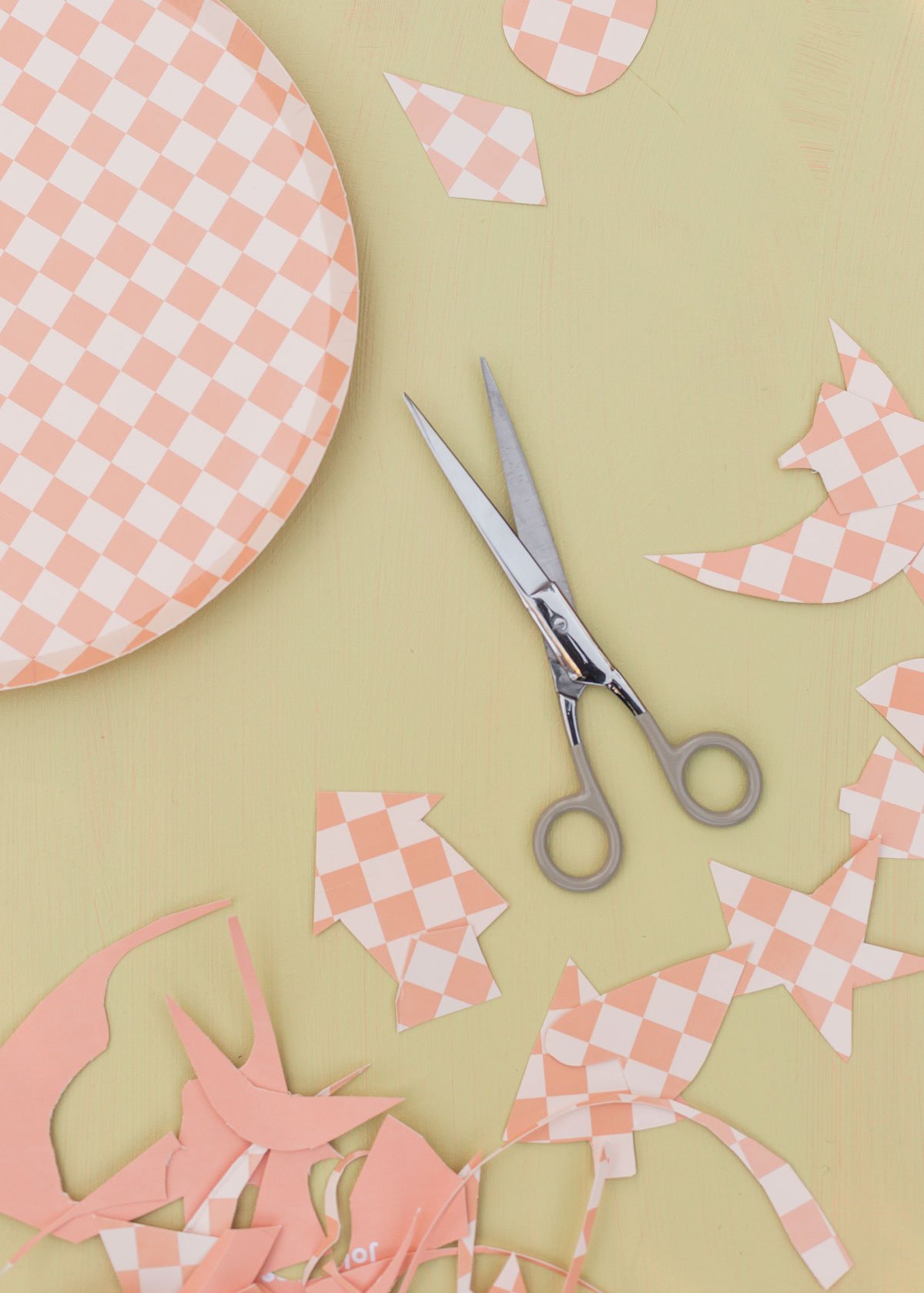 scissors and checkered paper plates being cut into different shapes to use an ornaments for christmas
