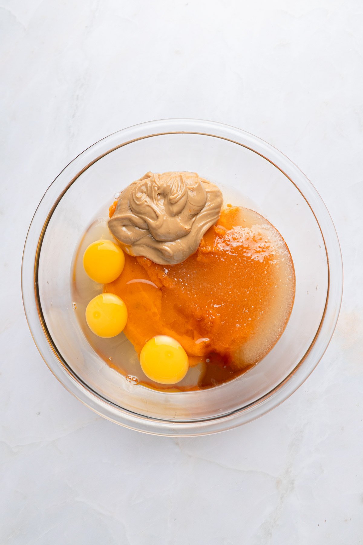 ingredients in a bowl for brownies, including eggs, peanut butter, sweet potato, and more