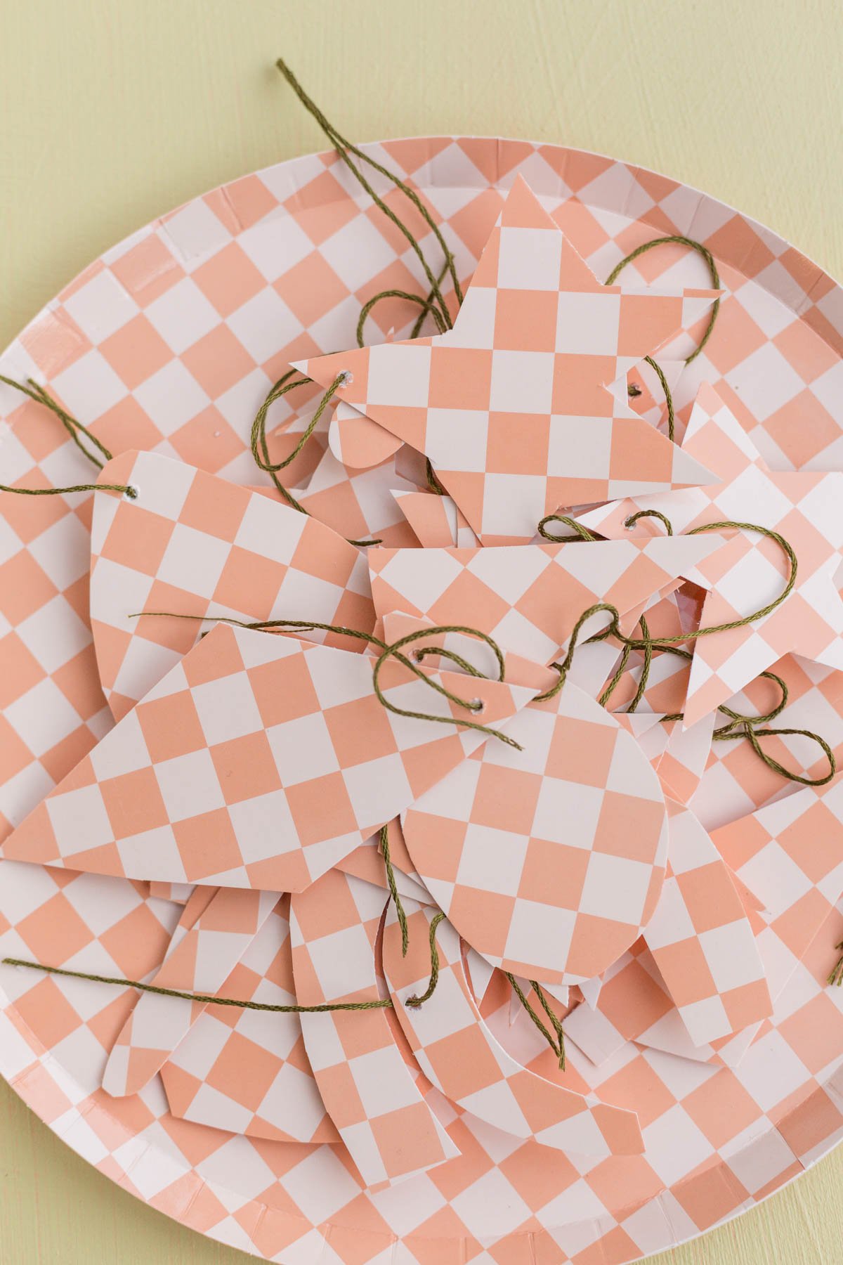 diy paper ornaments in checkered patterns, sitting on top of paper plate in a pile