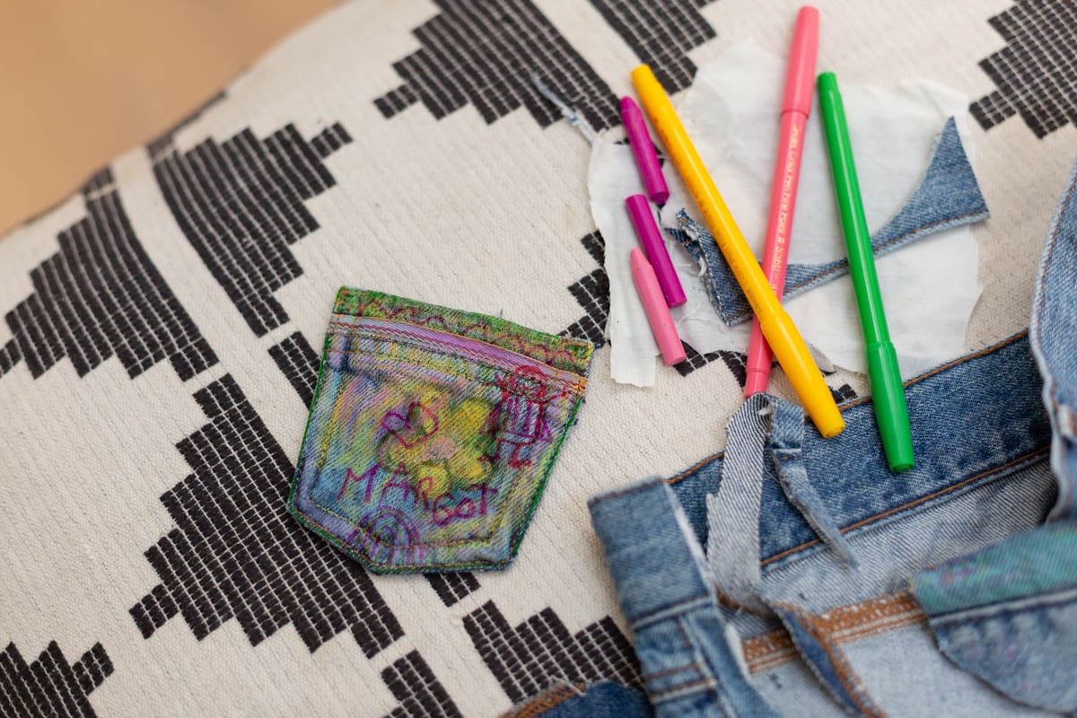 small denim pouch with kids doodles drawn onto it, with markers