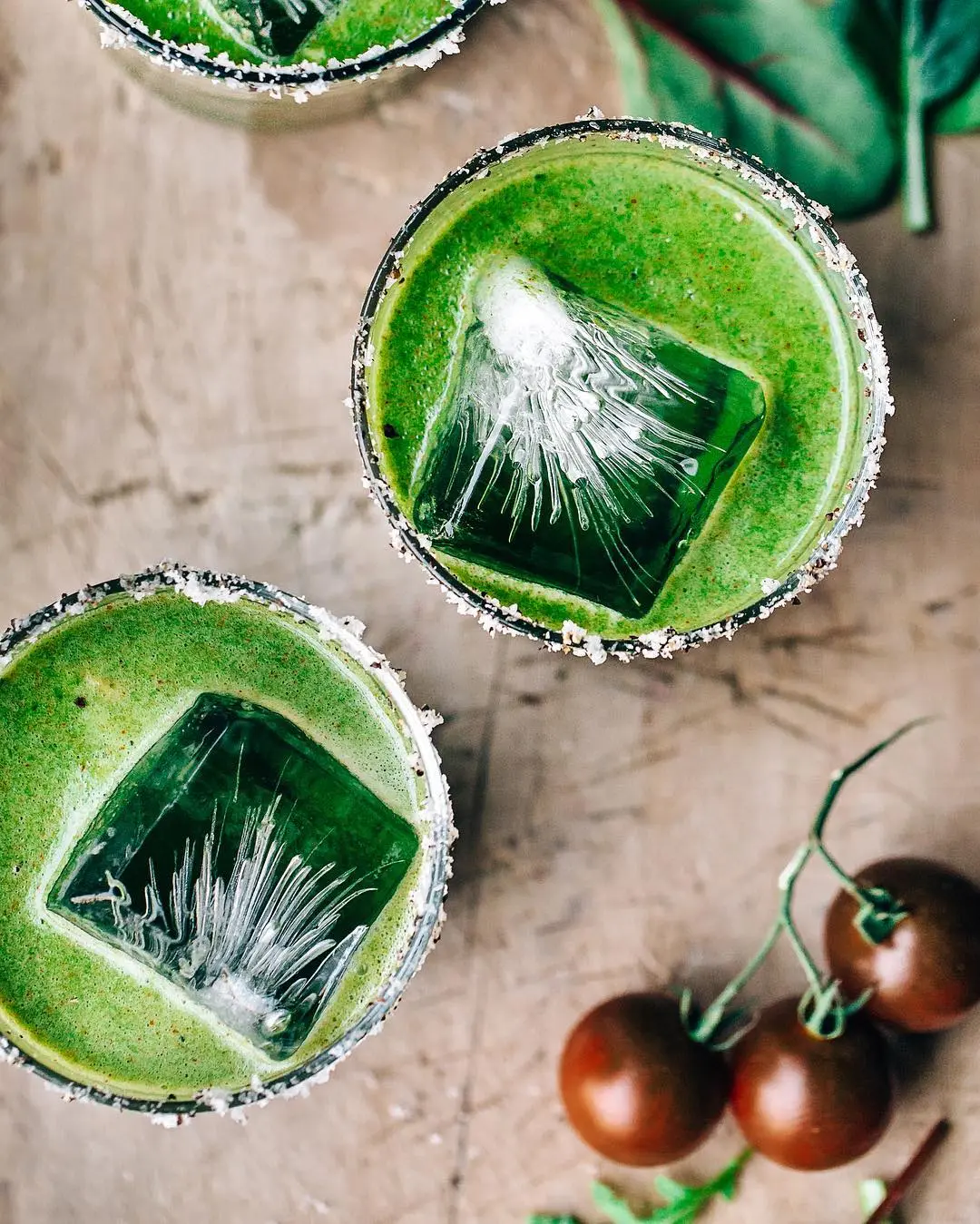 bright green cocktail overhead, with large blocks of ice in short glasses