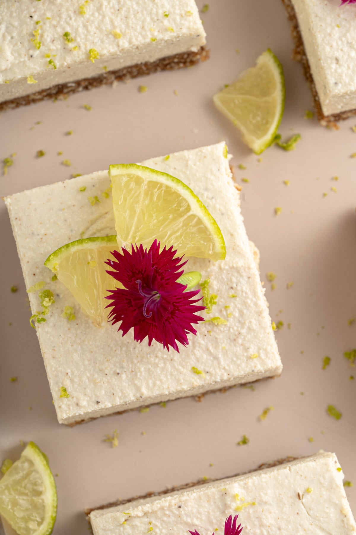 overhead of homemade key lime bars with edible flowers and thin lime slices on top