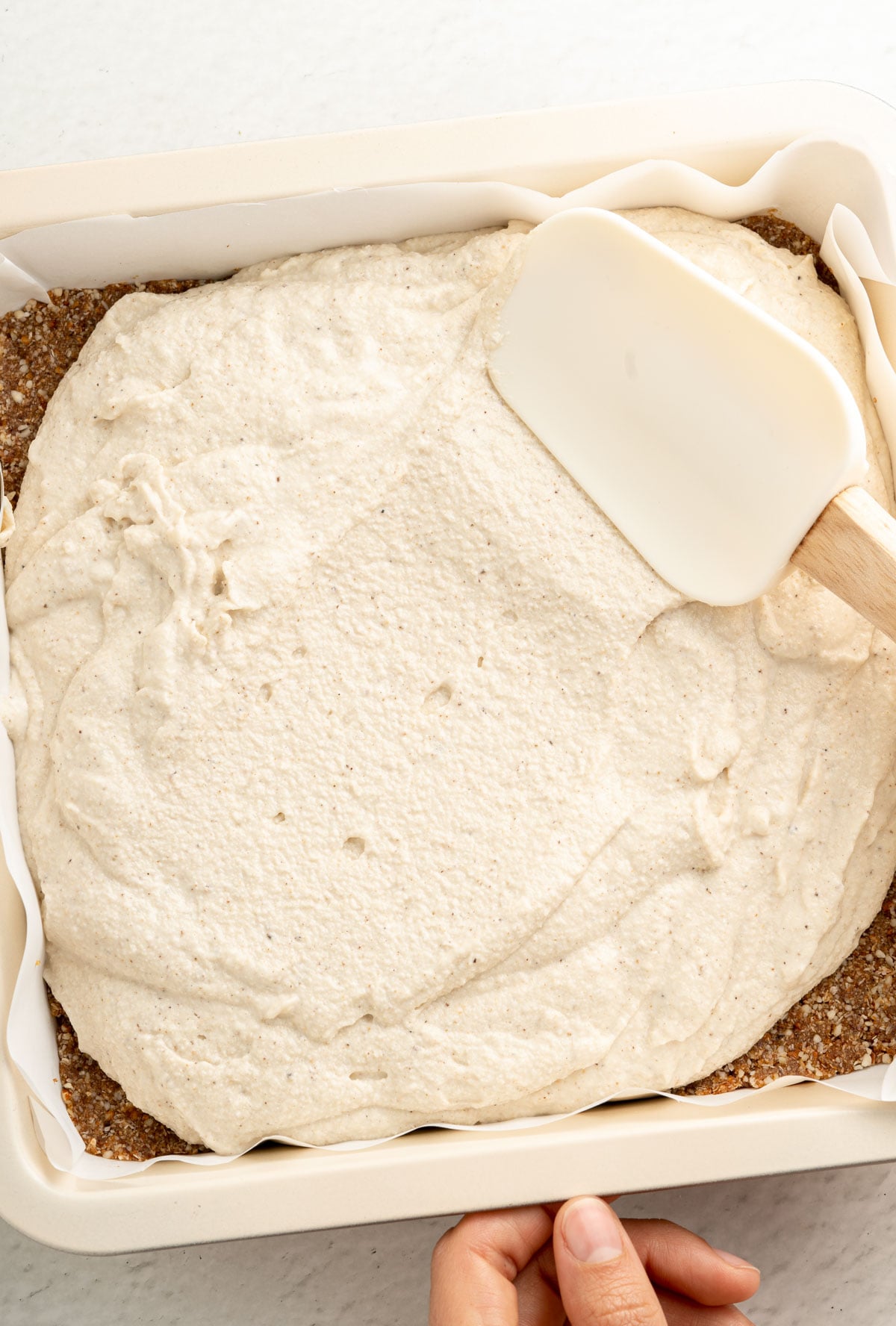 spreading key lime bar filling onto almond crust in a pan